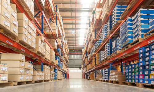 Rows of shelves with goods boxes in huge distribution warehouse at industrial storage factory.